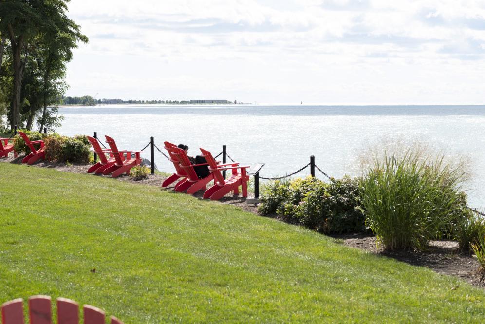 A student lounges in a red chair along Lake Michigan.